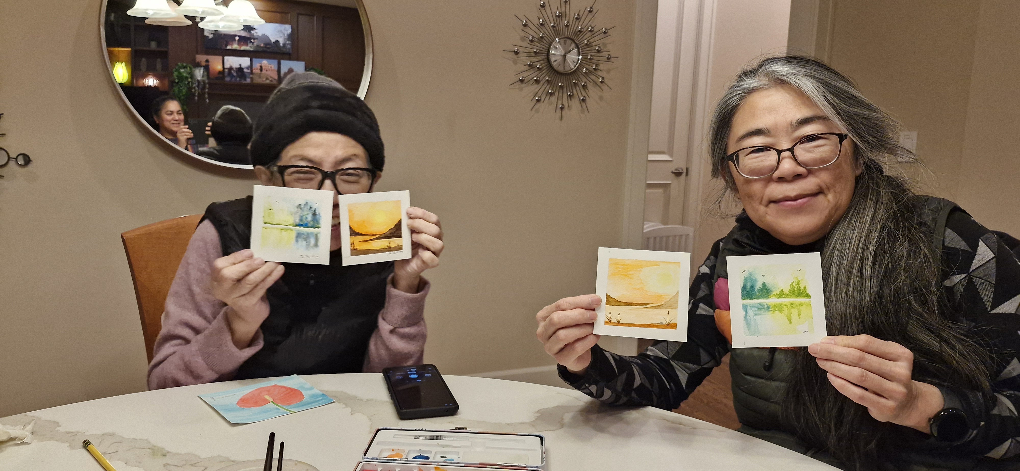 Adult workshop participants displaying their landscape paintings